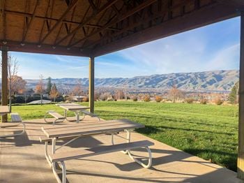 A patio with picnic tables and a view of the mountains
